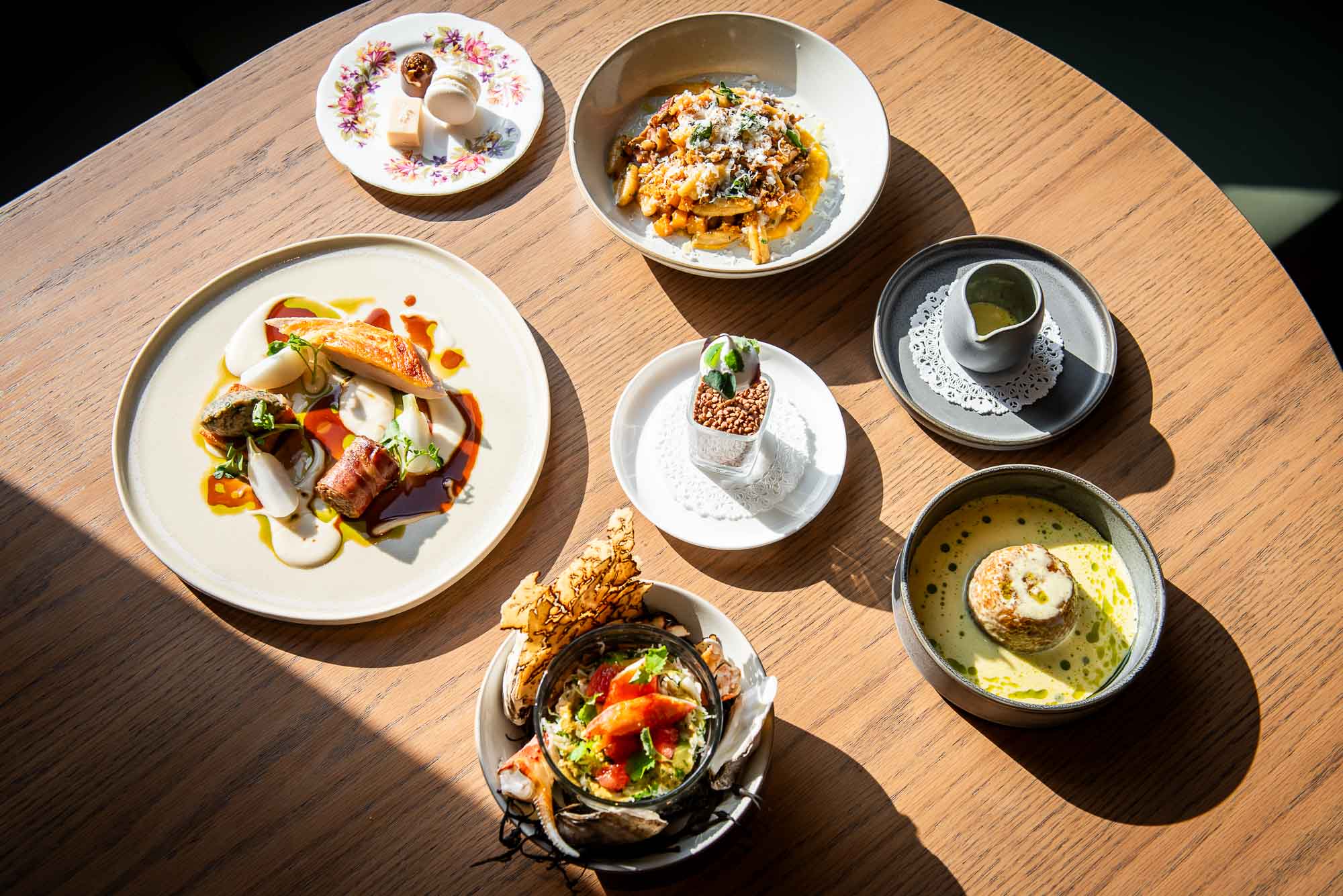 Tasting menu dishes on a wood top table at The Dorset in Toronto